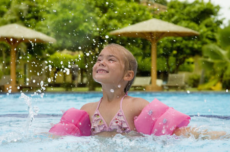 Little girl having fun splashing water in a pool  
