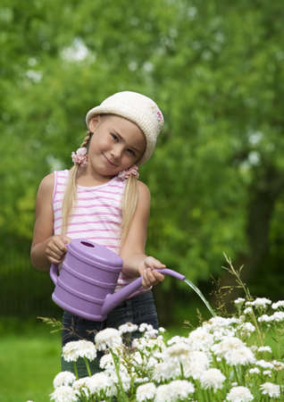 Little girl watering flowers in a gardenの写真素材