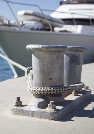 Bollard on a harbor pier with a rope tied around itの写真素材