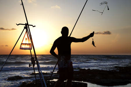 Fisherman silhouette catching a fish. Horizontal shotの写真素材
