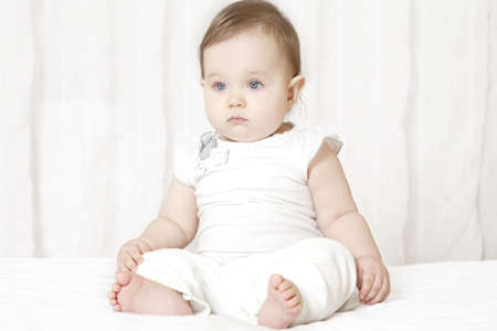 Adorable Caucasian toddler girl sitting on the bedの写真素材