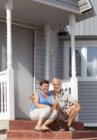 Mature loving couple sitting on the front stepsの写真素材