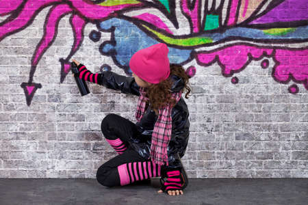 Teenager girl painting a graffiti on a wallの写真素材