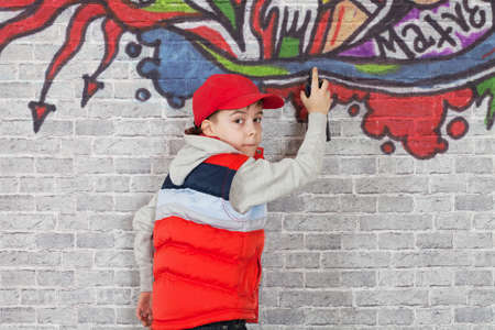 Teenager boy painting a graffiti on a brick wallの写真素材