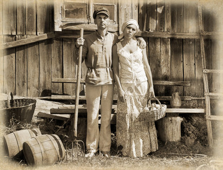 Couple in a stiff, old classic retro pose, standing in front of wooden stableの写真素材