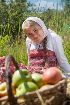 Summer outdoor portrait of cute little girl sitting on meadow with apple basket
の写真素材