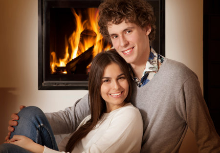 Portrait of lovely couple in front of a fireplace,  looking at cameraの写真素材