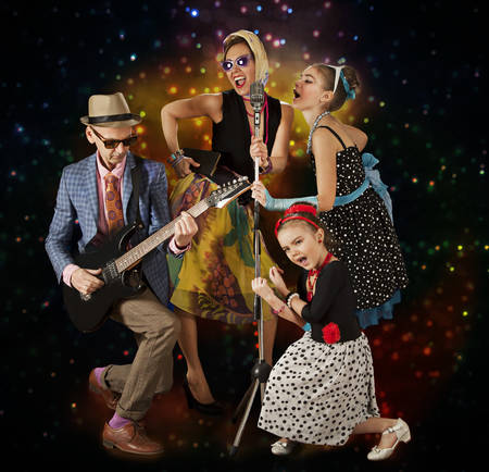 Rockabilly family band playing music and singing on a black background with glowing lightsの写真素材