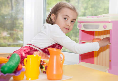 Little cute girl is playing in her toy kitchenの写真素材