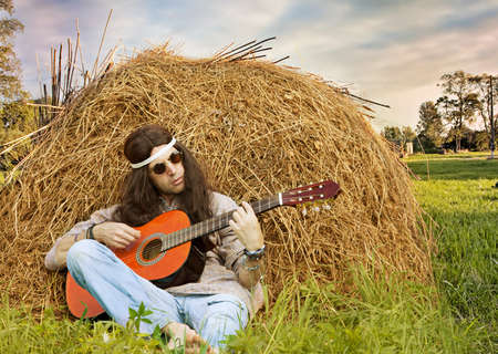 Long Haired Middle Aged Hippie Man Playing Guitar Outdoors