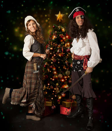 Picture of a carnival couple posing over Christmas tree on a colorful background with glowing lightsの写真素材