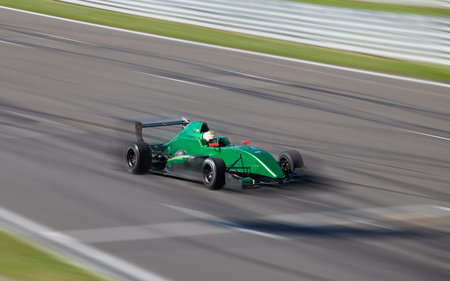 Race car F2 racing on speed track with motion blur at sunny summer day