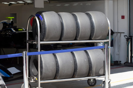 Wheels   are standing in row in the rack next to the garage