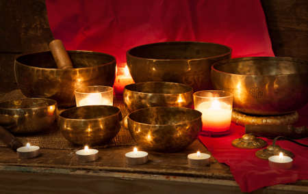 Tibetan singing bowls with burning candles on a red backgroundの写真素材