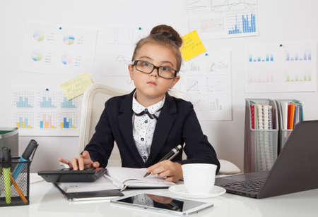 Portrait of pretty, seven years old,  business girl at office deskの写真素材