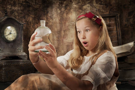 Portrait of a beautiful young girl expresses wonder holding the magic potion in her hands dressed as Alice in Wonderland indoor
の写真素材