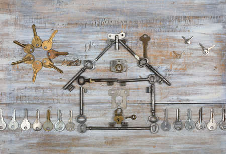 Background with a house shape with a fence and the sun made with old keys on old painted wooden boards. Top viewの写真素材