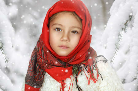 Portrait of a little girl in a red scarf in a winter forestの写真素材