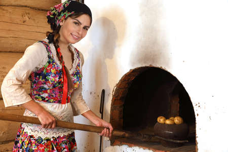 Young woman cooking in a typical Russian stoveの写真素材