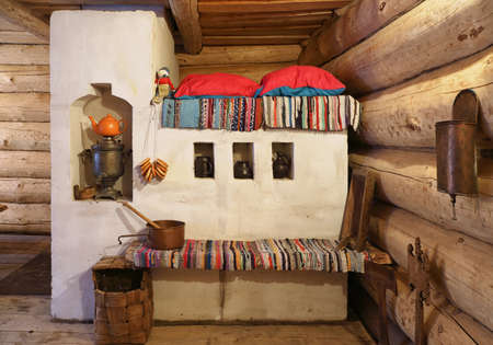 Traditional Russian stove with utensils in a wooden log hutの写真素材