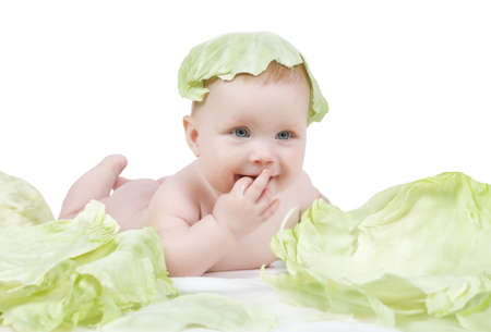 Little baby girl lying with cabbage leaf on her head on a white backgroundの写真素材