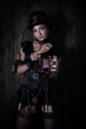 Young pretty girl in the style of a steampunk over wooden vintage backgroundの写真素材