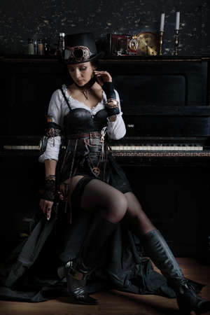 Pretty young steampunk girl sits at a piano in a vintage interiorの写真素材