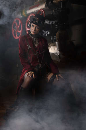 Young attractive steampunk woman sitting on a chair in steam over industrial background with pipes and valves
の写真素材