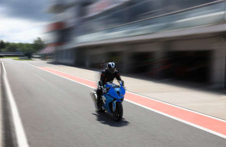 Motorcyclist on a racing motorcycle back from the race track to the pits, background with motion blurの写真素材