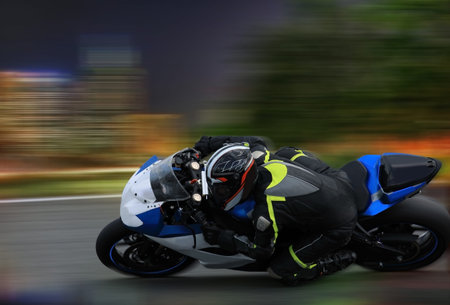 Racing bike rider leaning into a fast corner at high speed on the nighttime background with motion...