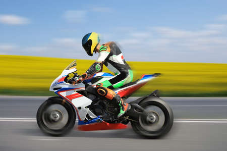 Racing bike rider racing outdoors at high speed with motion blur on a colorful backgroundの写真素材