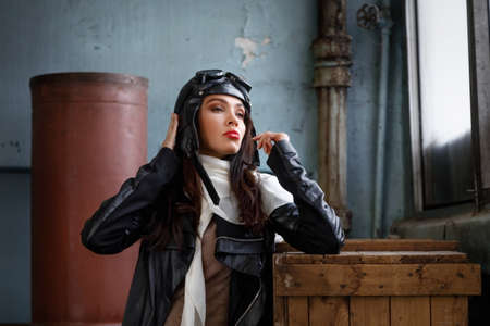 Portrait of a nice brunette girl in retro pilot costume in flight hangarの写真素材