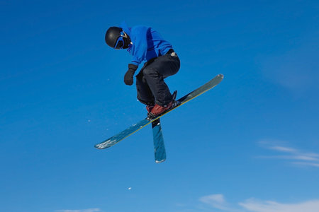 Skier jumps high in air with blue sky background. Livigno, Italyの写真素材