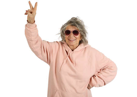 Smiling old woman shows a victory sign isolated on a white backgroundの写真素材