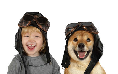 Portrait of a cute little blonde girl in the pilot's helmet and Shiba inu dog in the studio. Isolated on a white backgroundの写真素材