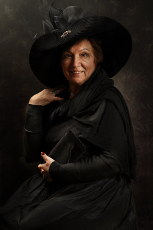 Portrait of an old woman in the Victorian style in the studio on an artistic background
