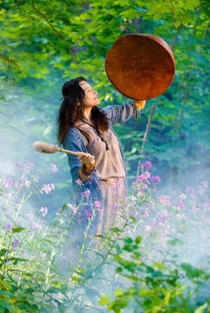Shaman woman playing her shaman sacred drum in the forest. Ethnic traditionsの写真素材