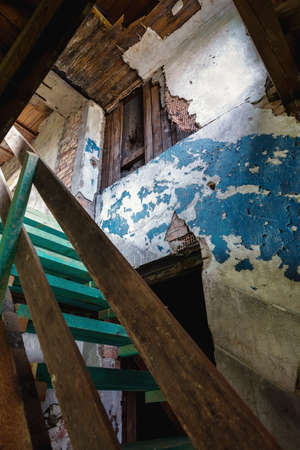 Interior with stairs leading to the attic and peeling blue walls in an old abandoned houseの写真素材