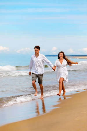 Nice couple of young people in love have fun on the sea coast against the blue skyの写真素材