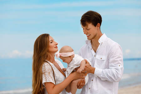 Young family with a baby relax on the sea coast on a sunny summer dayの写真素材
