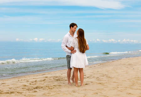 Hugging couple of young people in love stands on the sea coast against the blue skyの写真素材