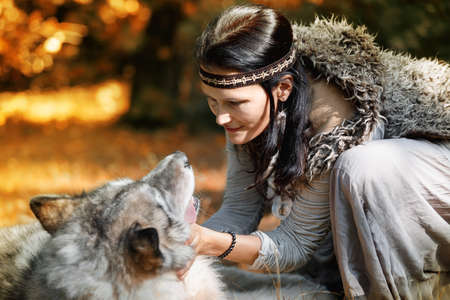 Forest dweller woman communicates with her wolf in the autumn forestの写真素材