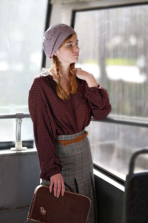 Young pretty freckled girl in retro style clothes standing in a wagon of a driving tramway. Transportation, travel and lifestyle concept.の写真素材