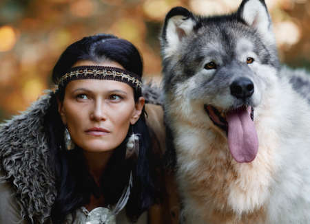 Portrait of a young charming woman with an Alaskan Malamute dog in the forest against the background of natureの写真素材