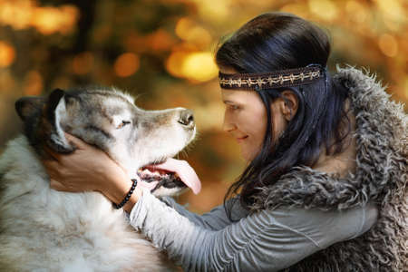 Portrait of a young pretty woman with an Alaskan Malamute dog in the forest against the background of natureの写真素材
