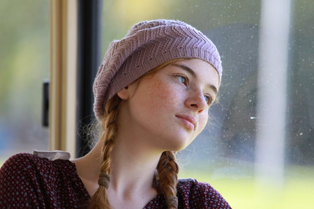 Portrait of a young dreamy freckled girl with pigtails dressed in retro style clothes in a wagon of...