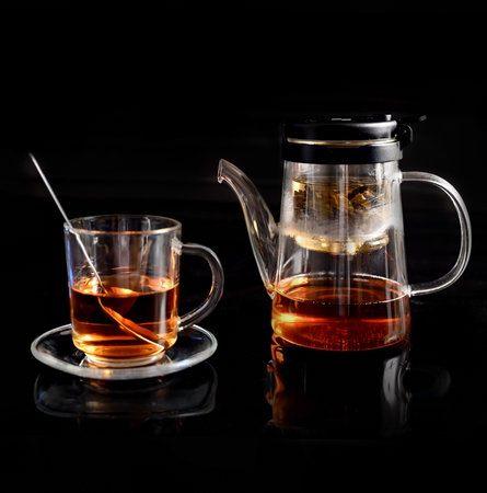 Glass transparent teapot and mug with hot green tea on black backgroundの写真素材
