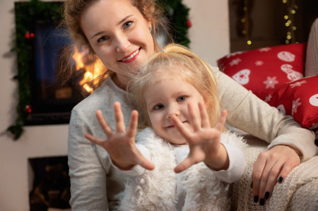 Celebrating Christmas at home. Happy young mother with little daughter enjoying their holiday time togetherの写真素材