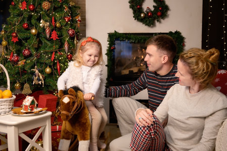 Young happy family celebrates Christmas by the fireplace and Christmas treeの写真素材
