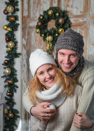 Young happy couple hugging in front of Christmas backgroundの写真素材